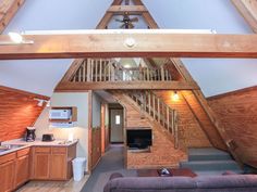 an open living room and kitchen area in a loft style home with wood paneling