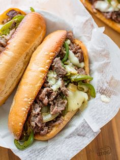 two sandwiches with meat, cheese and green peppers