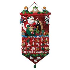 a cross stitch christmas stocking hanging on a wall with santa claus and other decorations