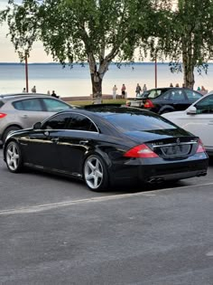 a black car parked in a parking lot next to the ocean