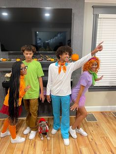 three children dressed up in costumes posing for a photo with an orange and green dog