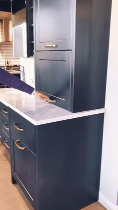 a woman standing in front of a kitchen counter with drawers and a refrigerator freezer