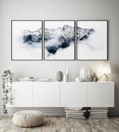 three paintings are hanging on the wall above a white cabinet in a modern living room