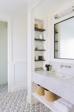 a bathroom with a sink, mirror and shelves