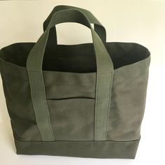 a green canvas tote bag sitting on top of a white table