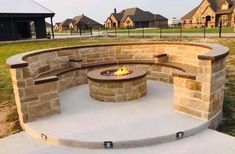 an outdoor fire pit in the middle of a park with houses in the back ground