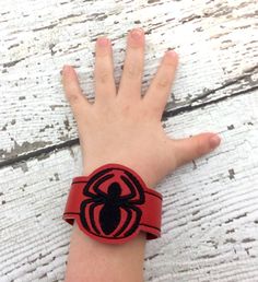 a child's arm with a spiderman wristband on it, sitting on a wooden surface