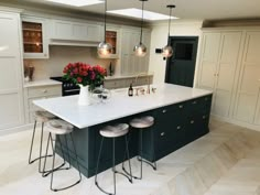 a large kitchen with an island in the middle and three stools on each side