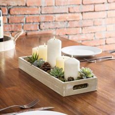 a wooden tray with candles and succulents in it sitting on a table