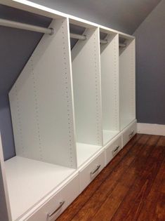 an empty closet with white shelves and drawers