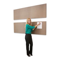 a woman standing next to two large panels holding a piece of paper and pointing at it