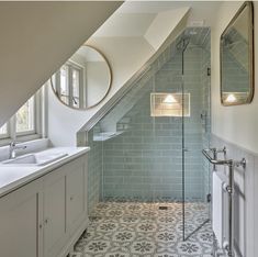 a bathroom with two sinks and a walk in shower under a slanted skylight