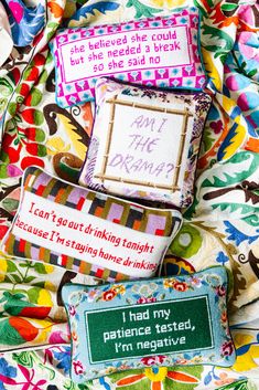 three different types of pillows on top of a colorful cloth covered bed with words written in small letters