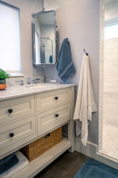 a bathroom with white cabinets and blue towels