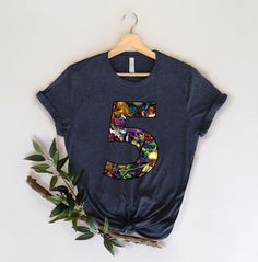 a t - shirt with the number five printed on it next to a leafy branch