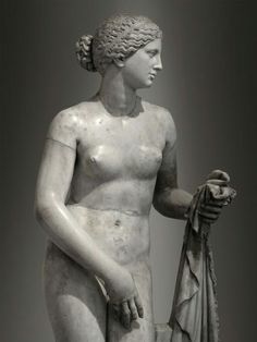 a statue of a woman holding a cloth and looking at something in her hand while standing