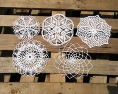 four white doily designs sitting on top of wooden pallets