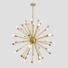 a gold chandelier with many lights hanging from it's center, on a gray background