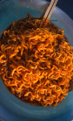 a blue bowl filled with noodles and chopsticks