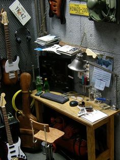 a room with guitars and other musical instruments on the wall, along with a desk