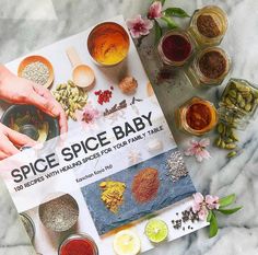 a cookbook with spices on top of it next to some bowls and spoons