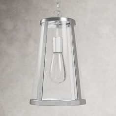 a glass light hanging from a ceiling fixture in a room with concrete walls and flooring