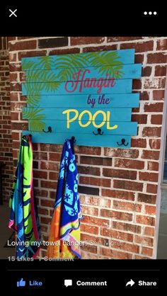 a wooden sign hanging on the side of a brick wall next to two beach towels