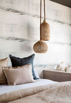 a bed with two hanging baskets on the headboard and pillows in front of it