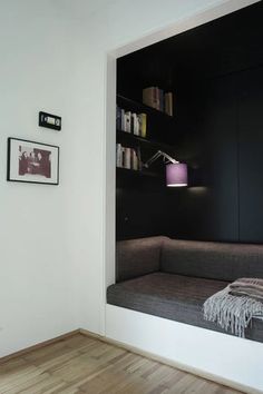 a black and white photo of a couch in the corner of a room with bookshelves