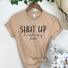 "Looking for the perfect botanical gardening gift? Check out our Plant Mom and Plant Dad tees, or our Plant Lover shirt that celebrates all things green! Our Plants tee is a must-have for any gardening enthusiast. Shop our collection of clothing and find the ideal gift for the plant lover in your life.  \"Shut up, its not too many plants\", sarcastic plant lover shirt. The Bella Canvas 3001 Unisex T-shirt is super soft cotton and quality colour. **The design is made to look \"vintage\" faded and will look slightly opaque to give that well-worn retro feel. ★ 100% Soft cotton (fibre content may vary for different colors) ★ Runs true to size * Unisex t shirt fits like a well-loved favorite, featuring a crew neck, short sleeves and designed with superior airlume combed and ring-spun cotton tha Cotton T-shirt With Plant Detail, Short Sleeve, Crew Neck Cotton T-shirt With Plant Details, Cotton Crew Neck T-shirt With Plant Details, Crew Neck Cotton Shirt For Gardening, Cotton Crew Neck T-shirt With Plants, Cotton Graphic Print T-shirt For Gardening, Cotton T-shirt With Graphic Print For Gardening, Cotton T-shirt With Letter Print For Gardening, Plant Shirts