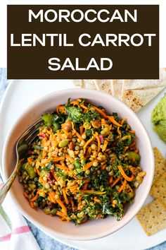 a white bowl filled with carrot salad next to crackers and guacamole