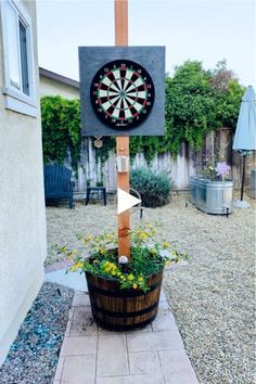 a wooden sign with a dart on it in the middle of a yard next to a potted plant