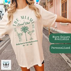 "Are you heading out on a Miami bachelorette trip and need some cute beach tees?  These personalizable bachelorette tees are perfect for all of your group.  Featuring cocktails and \"The Miami Club\", along with your name and destination.    These vintage style tees can be sized up for an oversized baggie look to wear on the beach or after the pool.    Available in Comfort Colors ™ T-Shirts in six beautiful colors.    Check my store for matching sweatshirts.   Product Quality *  Comfort Colors© t-shirts are made of 100% ultra-soft ringspun cotton featuring a relaxed fit and vintage look.    For a trendy oversized look, order 1 to 2 sizes up from your normal size.   They are a little thicker than other t-shirts and have a vintage feel and look to them.   This design features a vintage overl Summer Crew Neck T-shirt For Bachelorette Party, Casual Short Sleeve T-shirt For Bachelorette Party, Summer Bachelorette Party T-shirt With Letter Print, White T-shirt For Bachelorette Party In Summer, Summer Honeymoon T-shirt With Short Sleeves, Casual T-shirt For Bachelorette Party In Summer, Casual Summer T-shirt For Bachelorette Party, Summer Honeymoon Short Sleeve T-shirt, Short Sleeve T-shirt For Summer Honeymoon