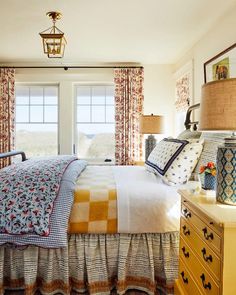 a bed sitting in a bedroom next to a window filled with pillows and blankets on top of it