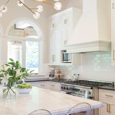 a large kitchen with white cabinets and marble counter tops, along with an island in the middle