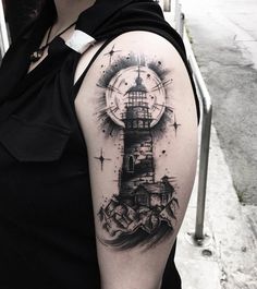 a woman's arm with a lighthouse and compass tattoo on the left side of her shoulder