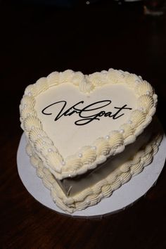 a heart shaped cake with writing on the top and bottom is sitting on a plate