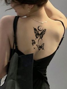 a woman with a tattoo on her back holding a shopping bag and looking down at the ground