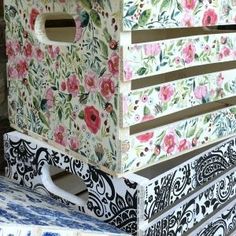 a flowered box sitting on top of a blue and white bench with flowers painted on it