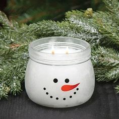 a frosty glass candle holder with a snowman face painted on the front and side