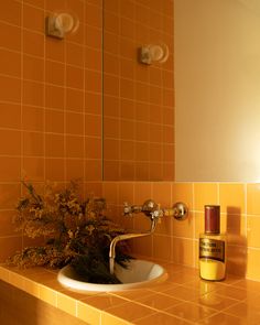 a bathroom sink sitting under a mirror next to a vase with flowers on top of it