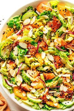 a white bowl filled with salad topped with lots of toppings and sliced almonds