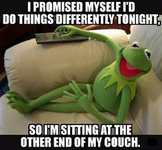 kermie the frog sitting on a couch with a remote control in his hand