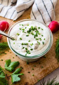 a glass bowl filled with ranch dip surrounded by radishes and cilantro