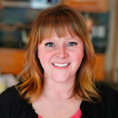 a woman with red hair and blue eyes smiling at the camera while wearing a black shirt