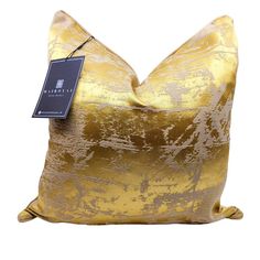 a gold and black pillow with a tag on it's side, in front of a white background