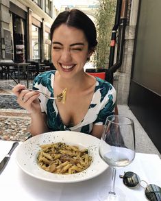 a woman sitting at a table with a plate of food in front of her smiling