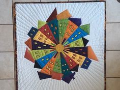 a quilted wall hanging with multicolored houses on it's center piece