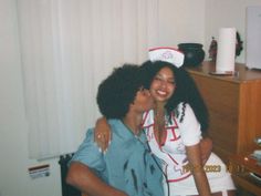 two women are hugging each other in the living room while wearing nurse's hats