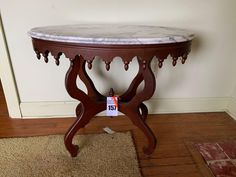 a marble top table on display in a room with hardwood floors and white walls, next to a carpeted floor